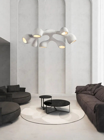 Odense Cocoon sculptural cloud pendant chandelier in white 7-head flat configuration hanging in a grand arched white hall above charcoal modular sofas and black marble nesting coffee tables — LivDecor
