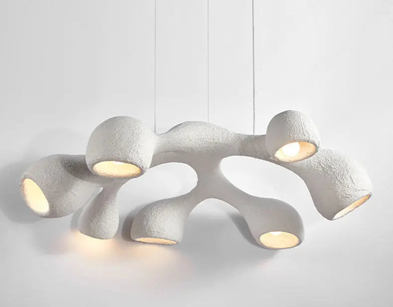 Odense Cocoon sculptural cloud pendant chandelier in white 7-head flat configuration fully lit with warm glow from all cavities showing textured plaster-like surface on a neutral background — LivDecor
