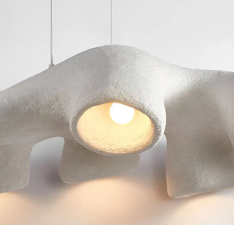 Odense Cocoon sculptural cloud pendant chandelier close-up of lit bulb inside textured white cavity casting warm glow on the artisanal plaster-like interior surface — LivDecor
