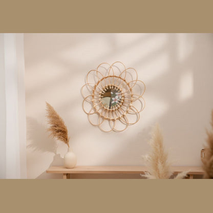 Round rattan flower wall mirror styled above a wood shelf with pampas grass in a warm neutral boho living space — LivDecor
