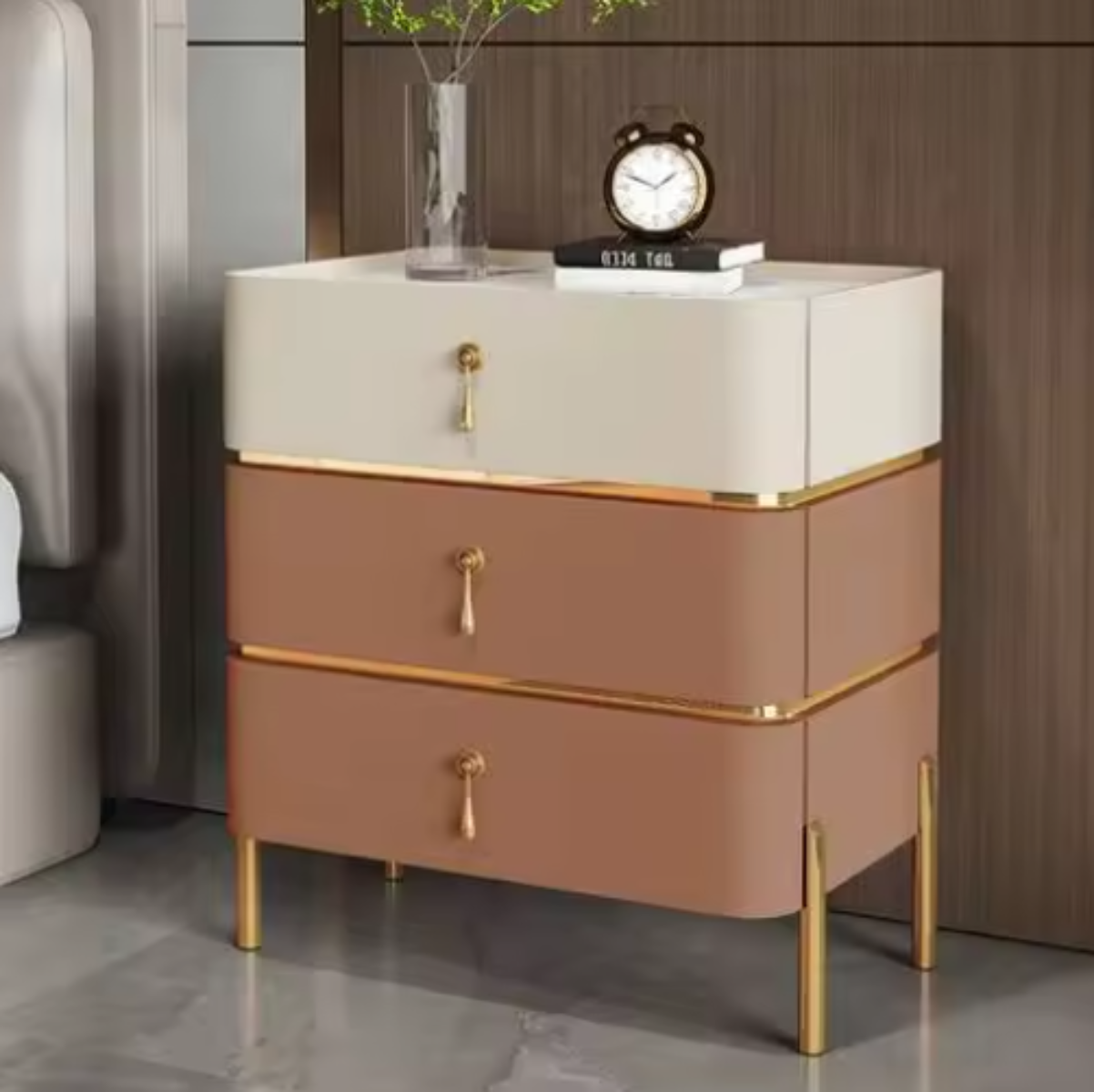 Slate top luxury two-tone beige and terracotta three-drawer nightstand with white slate top, gold trim, drop-pull handles and slim tapered gold legs styled beside a bed against a walnut wall — LivDecor
