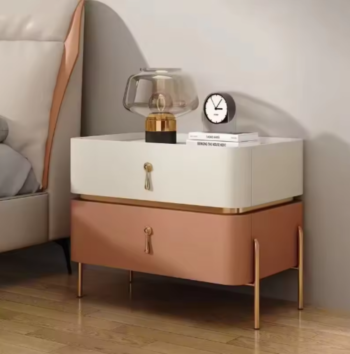 Slate top luxury two-tone beige and terracotta two-drawer nightstand with gold trim, drop-pull handles and slim tapered gold legs styled beside a leather bed with a glass lamp — LivDecor
