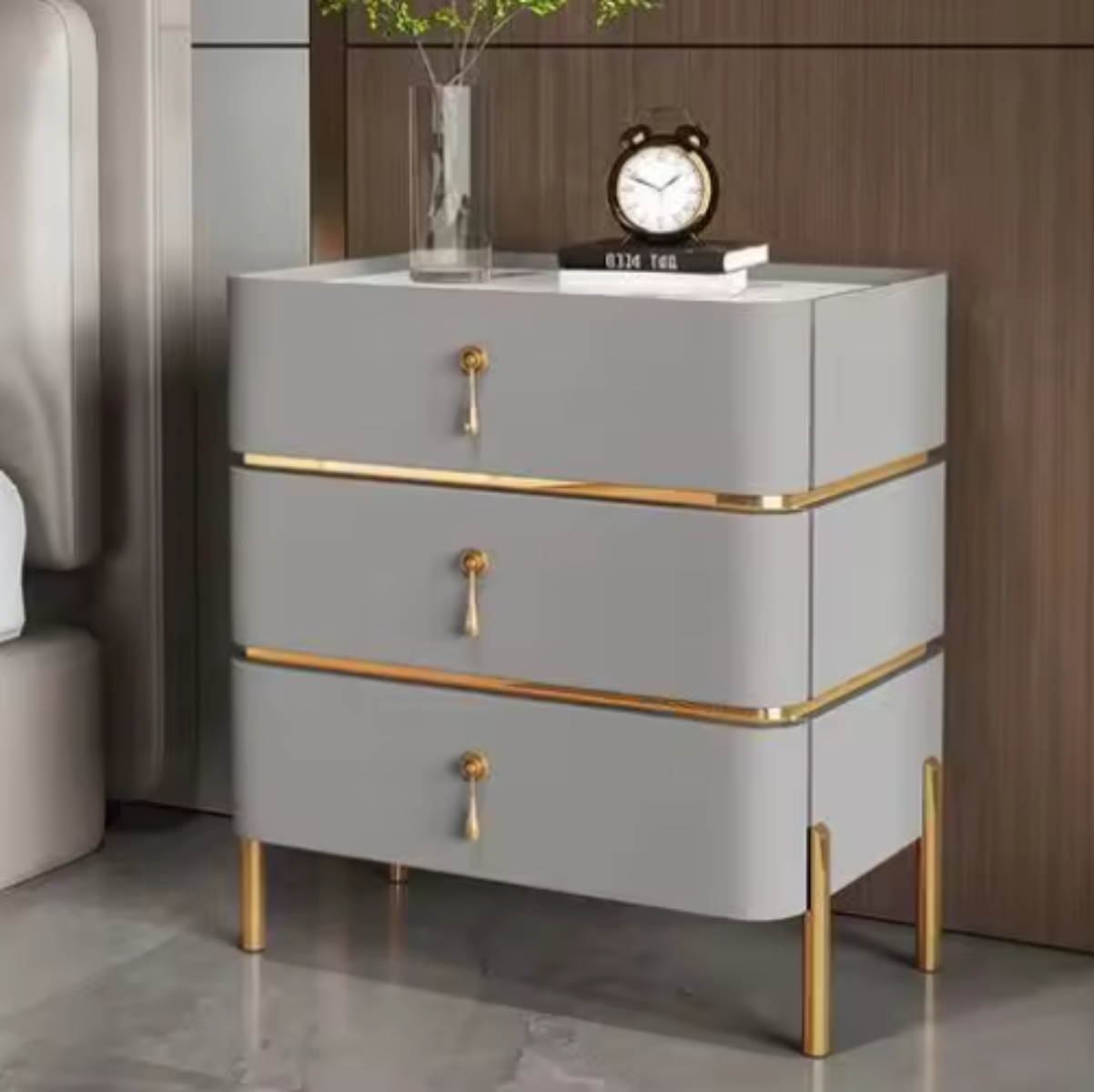 Slate top luxury dove grey three-drawer nightstand with white slate top, gold trim, drop-pull handles and slim tapered gold legs styled beside a bed against a walnut wall — LivDecor
