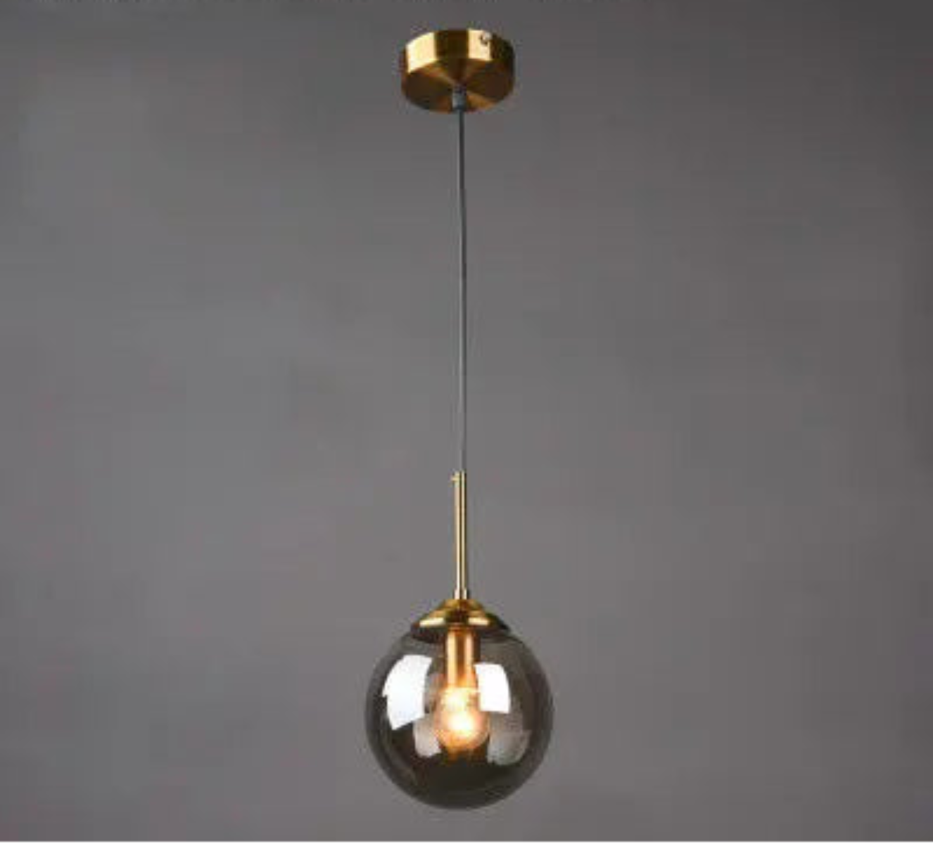 Single smoke grey glass globe pendant light on gold cord and ceiling mount displayed against a neutral grey background — LivDecor