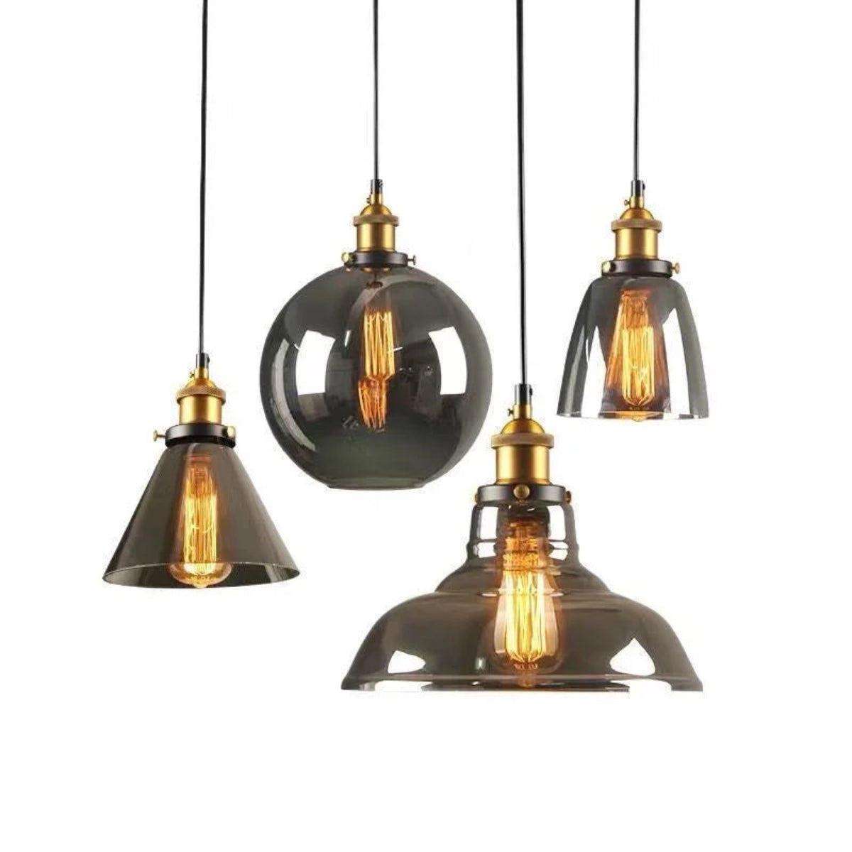 Four smoke grey glass pendant lights in cone, globe, dome and bell shapes with brass fittings and glowing Edison filaments displayed against a pure white background — LivDecor