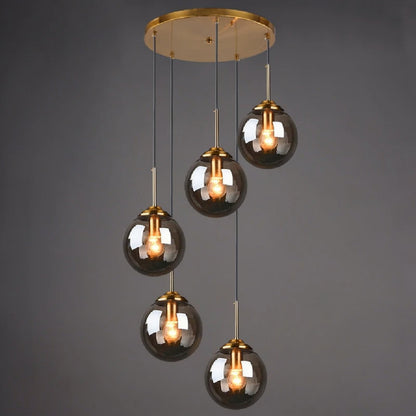 Smoky grey glass globe pendant light, 5-light drop configuration in a staggered spiral cluster on gold cords from a round ceiling mount, lit against a dark grey background — LivDecor
