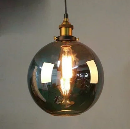 Smoky grey glass globe pendant light with brass Edison fitting and lit filament bulb glowing warmly against a neutral wall — LivDecor
