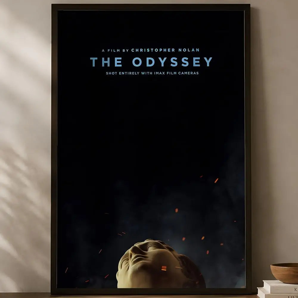 The Odyssey Christopher Nolan minimalist black IMAX poster with fallen marble statue face and ember sparks displayed on a warm natural light shelf — LivDecor
