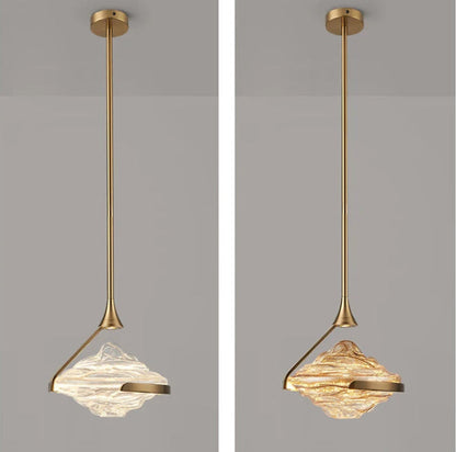Side-by-side comparison of clear and amber wave glass geometric pendant lights both on gold stems with round ceiling canopy against a grey background — LivDecor